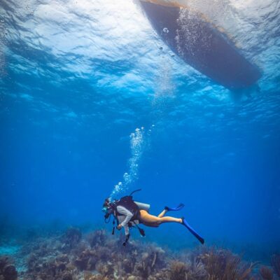 Scuba diver below boat at Belize Glover's Reef